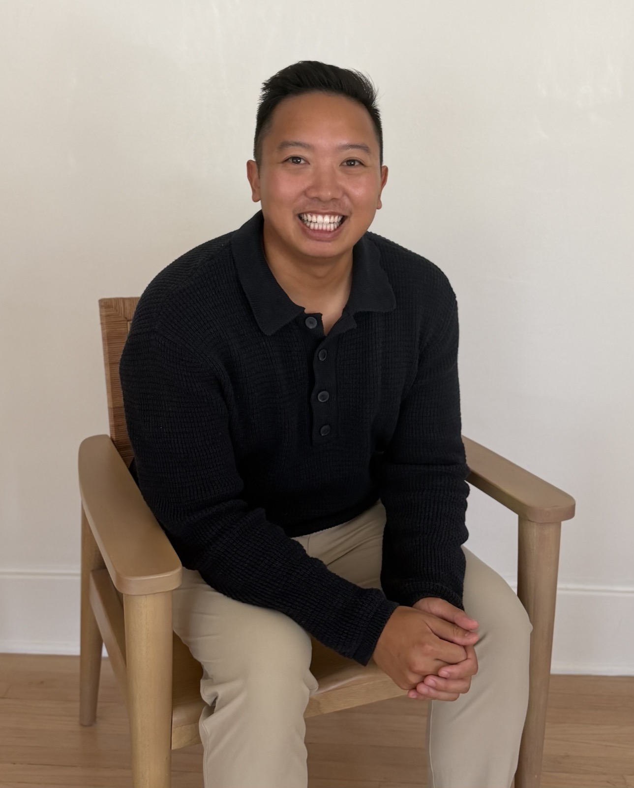 Dr. Binh Pham, seated in a wooden chair, smiling